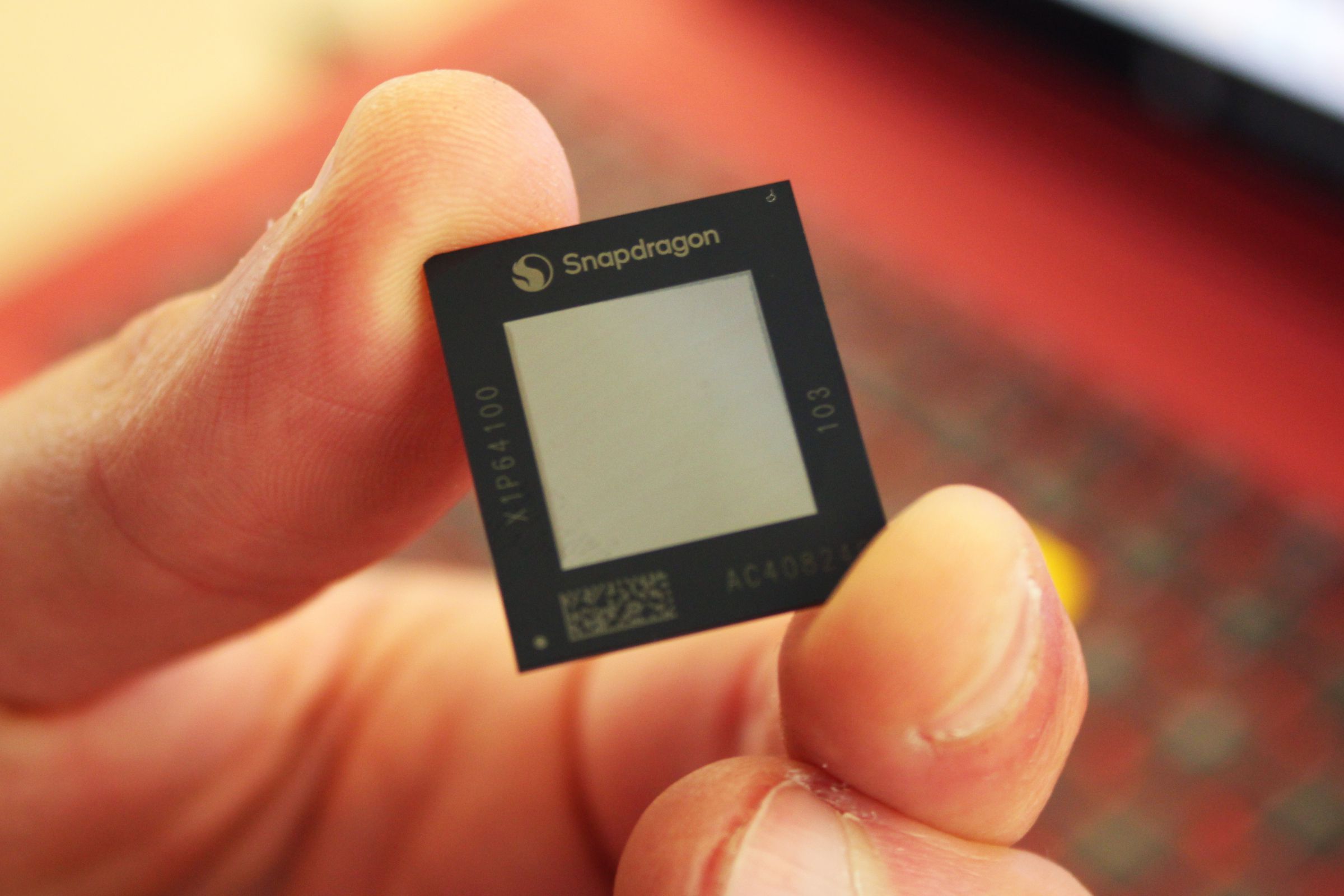 A close-up of a tiny computer chip held between someone’s fingers.