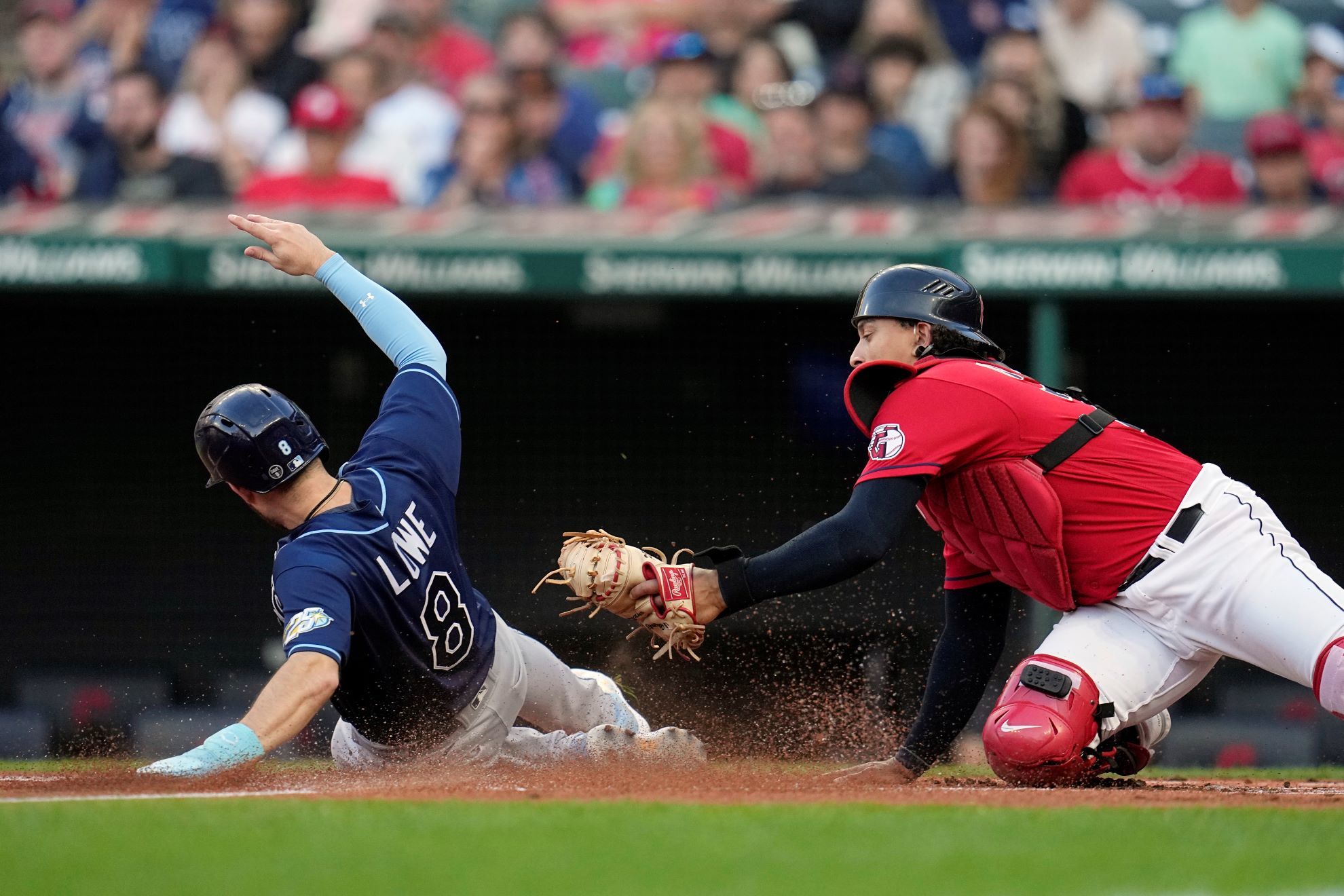 Tampa Bay Rays Brandon Lowe (8) scores under the tag attempt of Cleveland Guardians catcher Bo Naylor during the first inning of a baseball game Friday