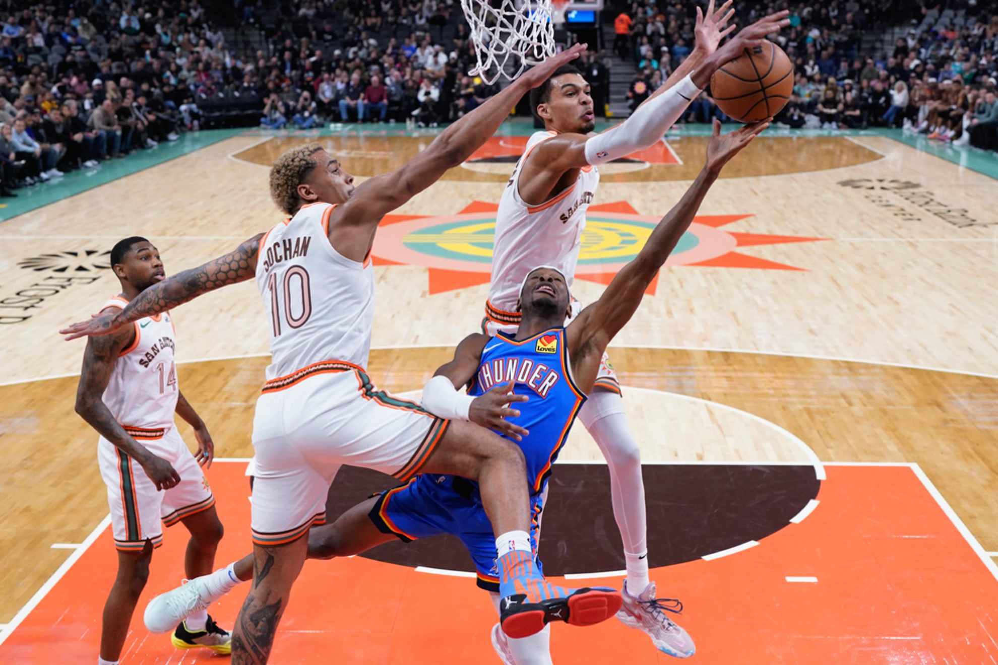 Shai Gilgeous-Alexander is blocked between Jeremy Sochan and Victor Wembanyama /