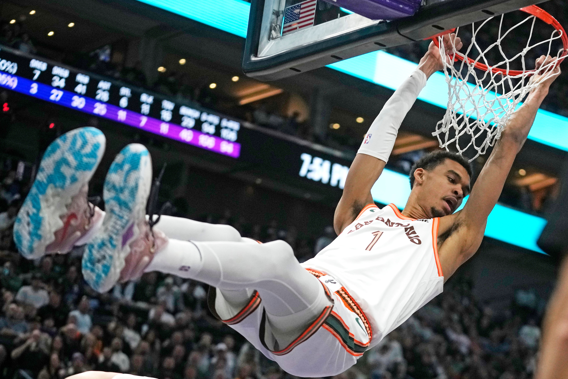 Look out below! Wembanyama hangs on the rim following a dunk on Sunday night.