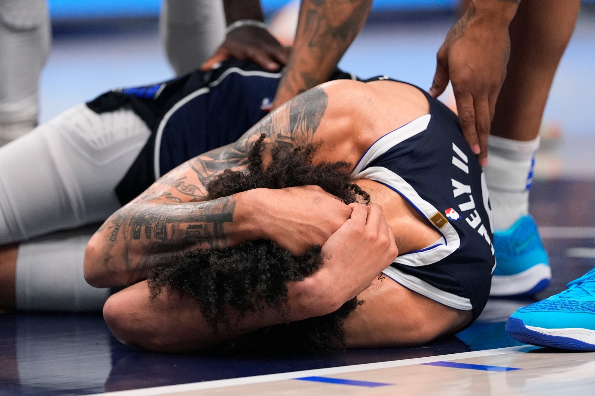 Dallas Mavericks center Dereck Lively II is checked on by teammates after a head injury during the first half in Game 3 of the NBA basketball Western Conference finals against the Minnesota Timberwolves