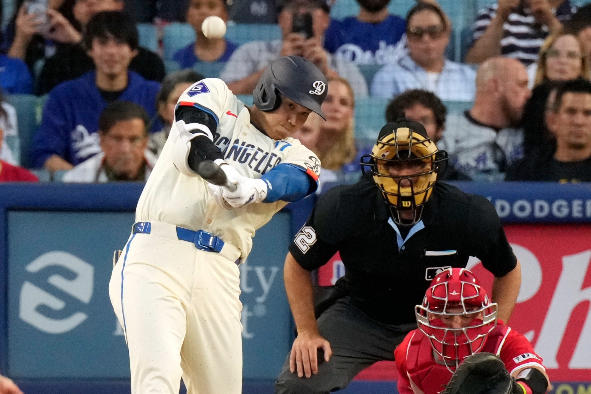 Los Angeles Dodgers Shohei Ohtani, left, hits a two-run home run as Los Angeles Angels catcher Logan OHoppe, right, watches along with home plate umpire James Hoye during the third inning of a baseball game Saturday, June 22, 2024, in Los Angeles. (AP Photo/Mark J. Terrill)