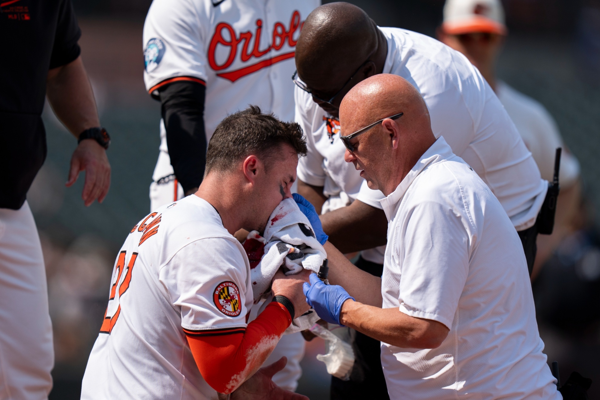 A trainer and coaches attend to Baltimore Orioles James McCann after he was hit by a pitch by Toronto Blue Jays starting pitcher Yariel Rodriguez during the first inning in the first baseball game of a doubleheader, Monday, July 29, 2024, in Baltimore. (AP Photo/Stephanie Scarbrough)