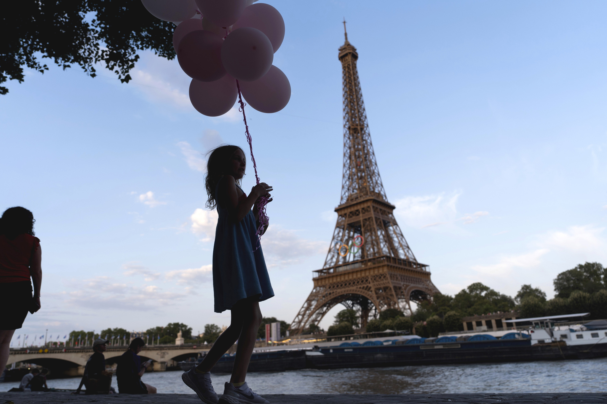 Jenna Baltes, 8, of St. Paul, Minn., holds balloons while walking along the  lt;HIT gt;Seine lt;/HIT gt;  lt;HIT gt;river lt;/HIT gt; in front of the Eiffel Tower with her family during the 2024 Summer Olympics, Monday, July 29, 2024, in Paris. (AP Photo/David Goldman)