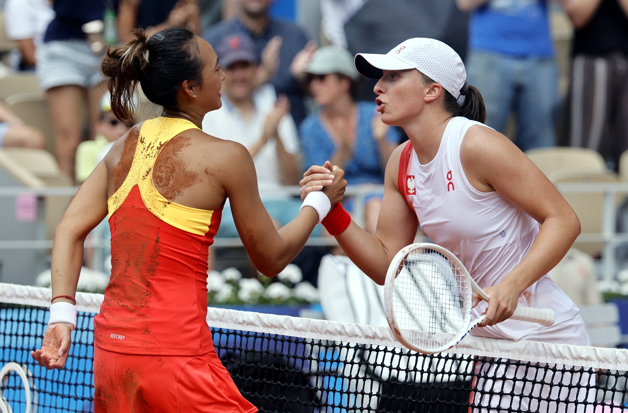 Qinwen Zheng (L) shakes hands with Iga Swiatek after winning their Womens Singles semi final match