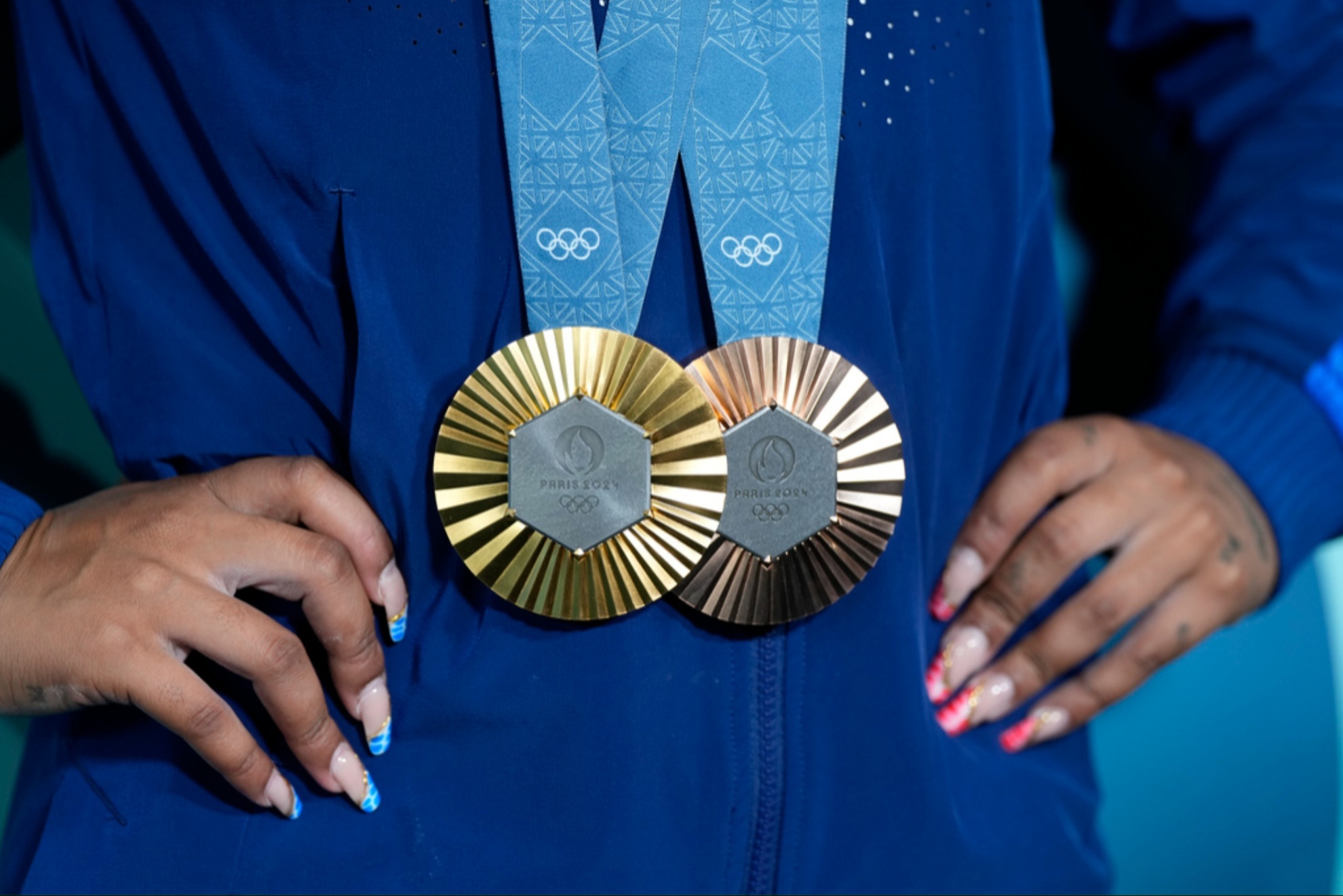 Jordan Chiles holds up her gold and bronze medals on August 5th.