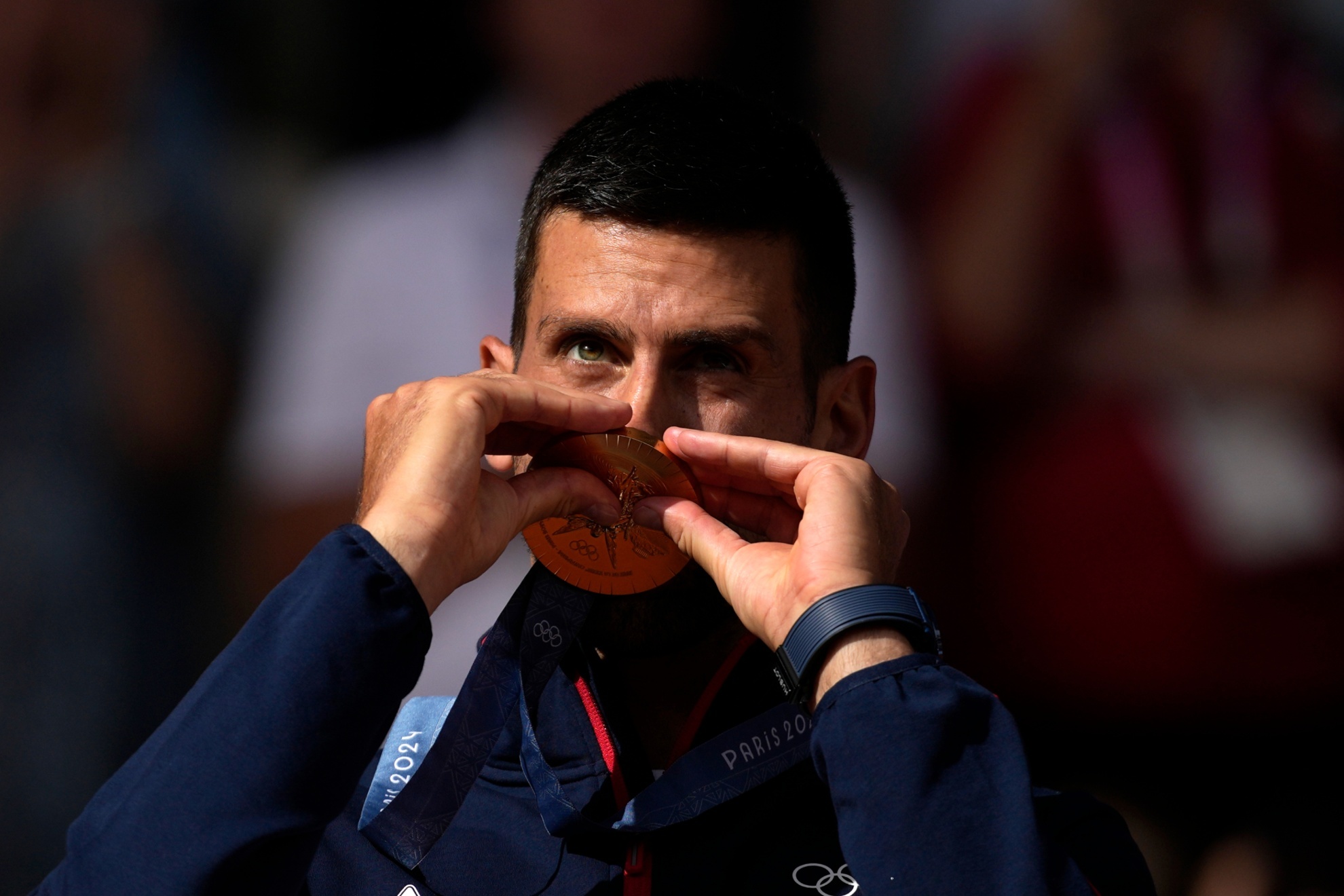 Serbias Novak Djokovic kisses his gold medal after defeating Spains Carlos Alcaraz during the mens singles tennis final at the Roland Garros stadium during the 2024 Summer Olympics, Sunday, Aug. 4, 2024, in Paris, France. Djokovic has won his first Olympic gold medal by beating Alcaraz 7-6 (3), 7-6 (2) in the 2024 Games mens tennis singles final. (AP Photo/Louise Delmotte)