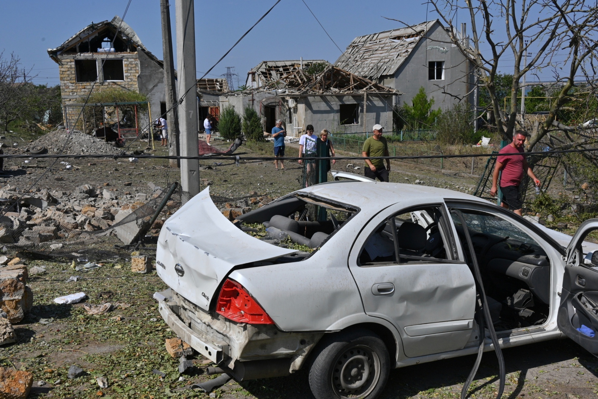 People walk in front of their damaged houses after Russian rocket attack in Usatove village near Odesa.