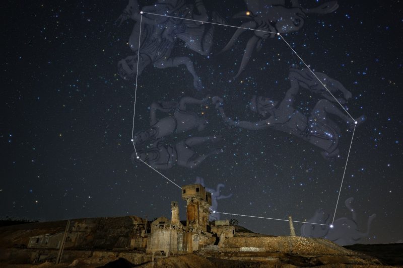 Night sky scene with hexagon and figures of constellation superimposed over top stars.