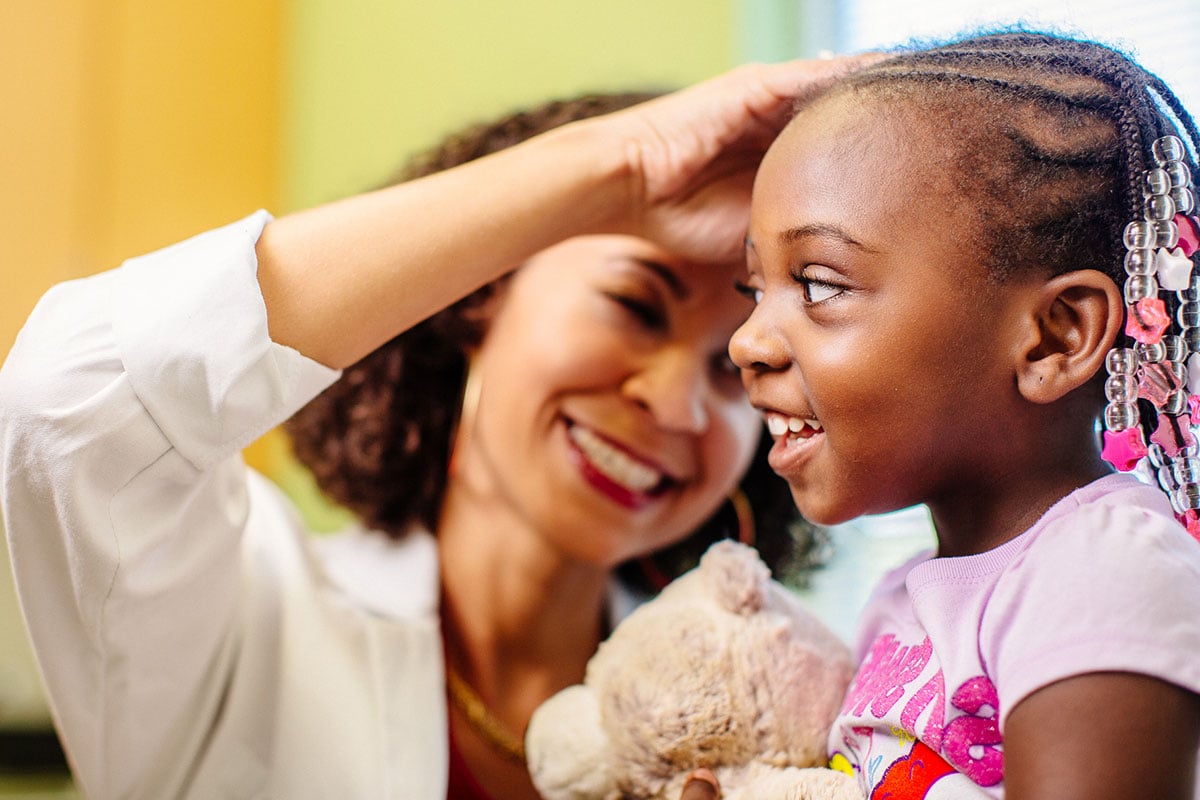 Provider checking a young girl's ear.