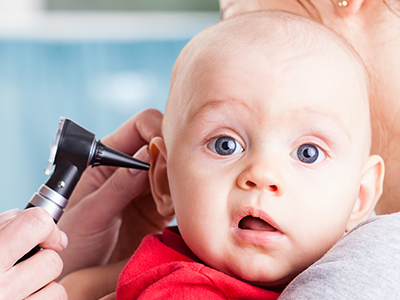 Pediatrician using otoscope on baby