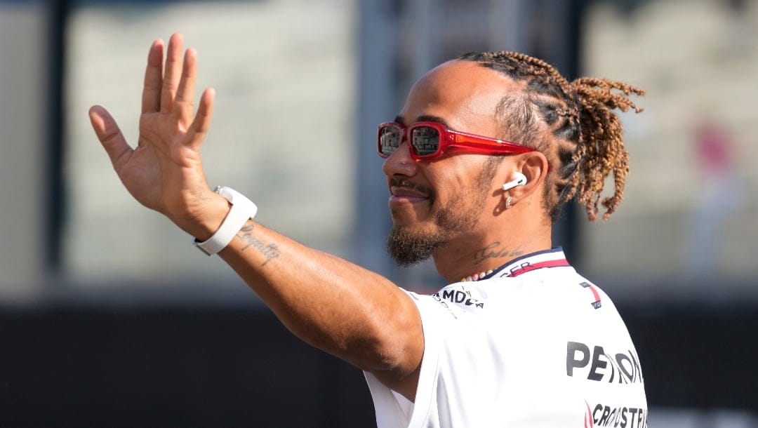 FILE - Mercedes driver Lewis Hamilton of Britain, waves as he arrives for the F1 drivers group picture ahead the drivers parade prior to the Abu Dhabi Formula One Grand Prix at the Yas Marina racetrack in Abu Dhabi, United Arab Emirates, Sunday, Nov. 26, 2023. Seven-time Formula One champion Lewis Hamilton has been linked with a shock move from Mercedes to Ferrari next year. (AP Photo/Kamran Jebreili, File)