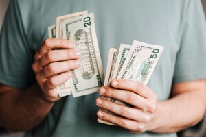 person counting money, with $10, $20, and $50 bills