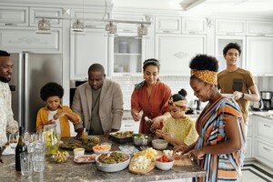 big family gathered around a countertop with an array of delicious-looking food spread out in front of them