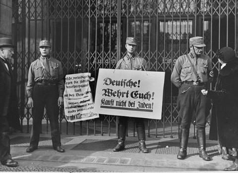 Members of the Storm Troopers (SA), with boycott signs, block the entrance to a Jewish-owned shop.