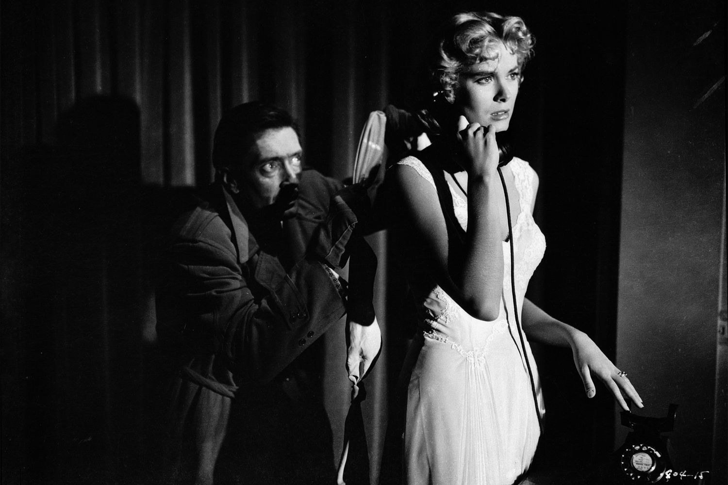1954: Anthony Dawson (1916 - 1992) sneaks up behind an oblivious Grace Kelly (1929 - 1982) in a tense scene from the film 'Dial M For Murder', directed by Alfred Hitchcock. (Photo via John Kobal Foundation/Getty Images)