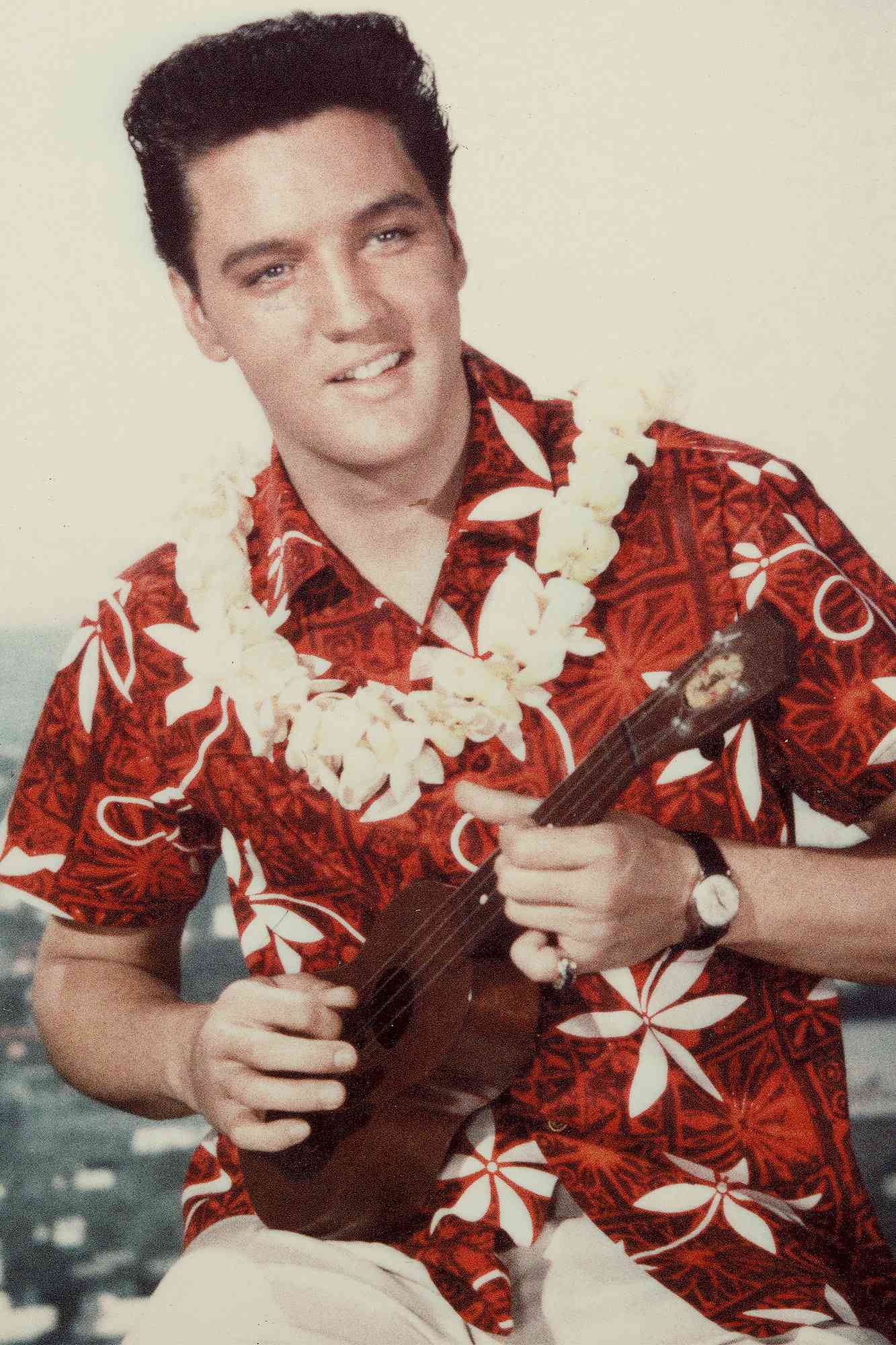 American rock n' roll singer Elvis Presley plays a ukelele, wearing a Hawaiian shirt and lei, in a still from the film 'Blue Hawaii,' directed by Norman Taurog, 1961. (Photo by Paramount Pictures/Courtesy of Getty Images)