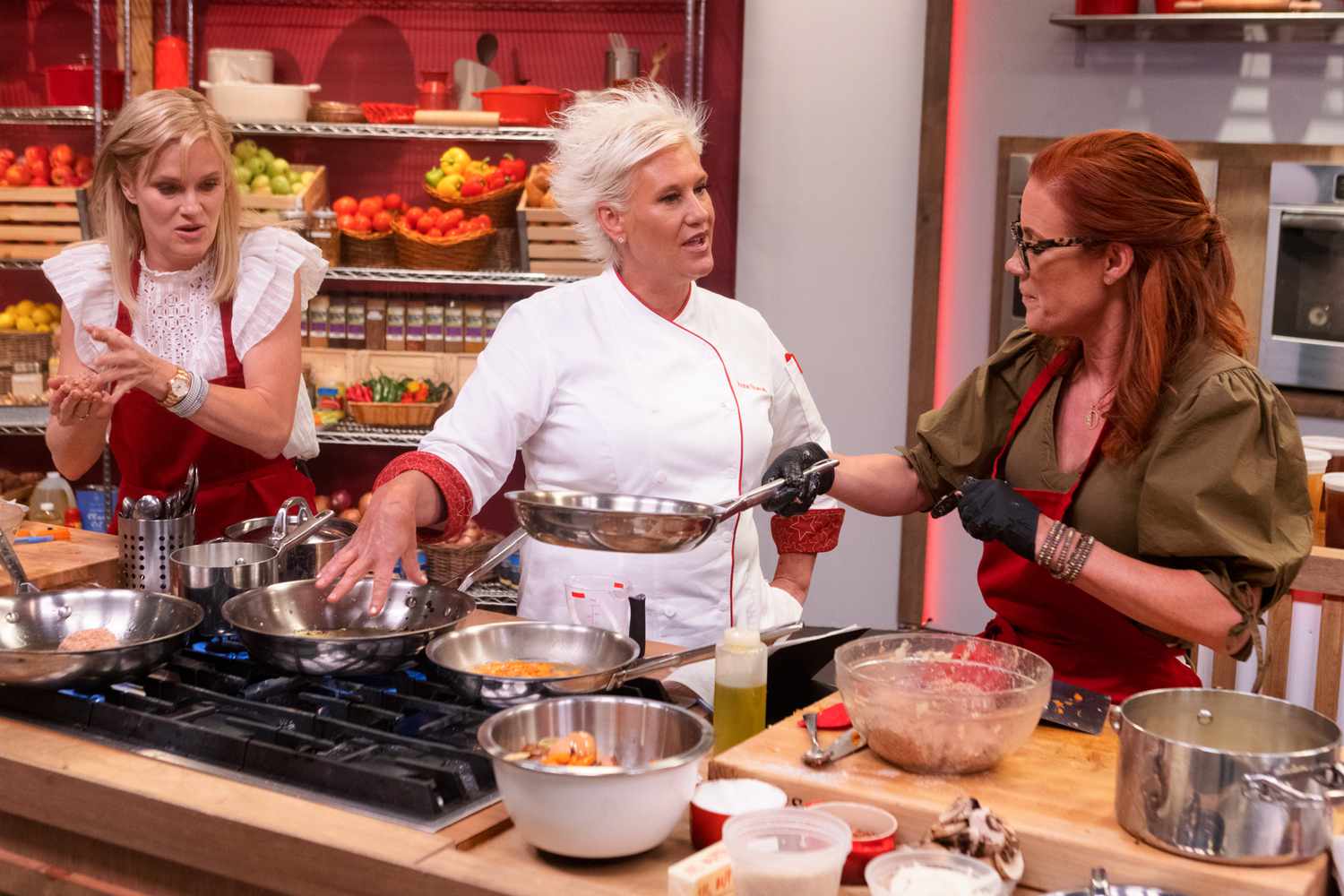 Mentor Anne Burrell checks in on red team recruits Nicholle Tom and Elisa Donovan as they cook during the main dish challenge, as seen on Worst Cooks in America, Season 23.