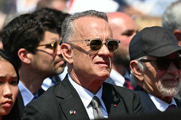 US actor Tom Hanks (C) and US director Steven Spielberg (R) attend the US ceremony marking the 80th anniversary of the World War II "D-Day" Allied landings in Normandy, at the Normandy American Cemetery and Memorial in Colleville-sur-Mer, which overlooks Omaha Beach in northwestern France, on June 6, 2024. The D-Day ceremonies on June 6 this year mark the 80th anniversary since the launch of 'Operation Overlord', a vast military operation by Allied forces in Normandy, which turned the tide of World War II, eventually leading to the liberation of occupied France and the end of the war against Nazi Germany. 