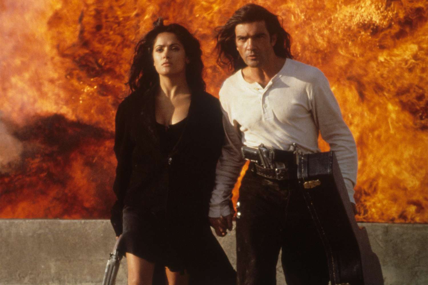 Antonio Banderas and Salma Hayek walking away from burning flames in a scene from the film 'Desperado', 1995. (Photo by Columbia Pictures/Getty Images)