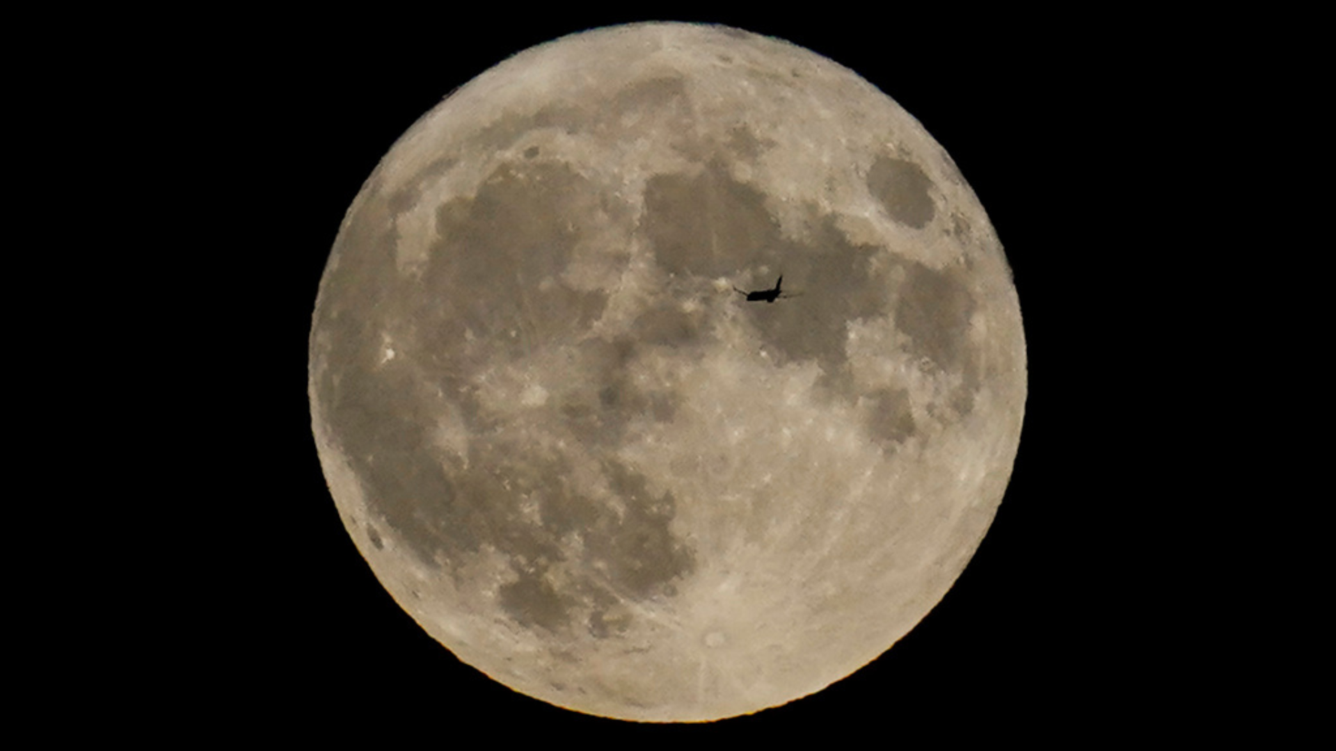 A plane passes in front of the moon.