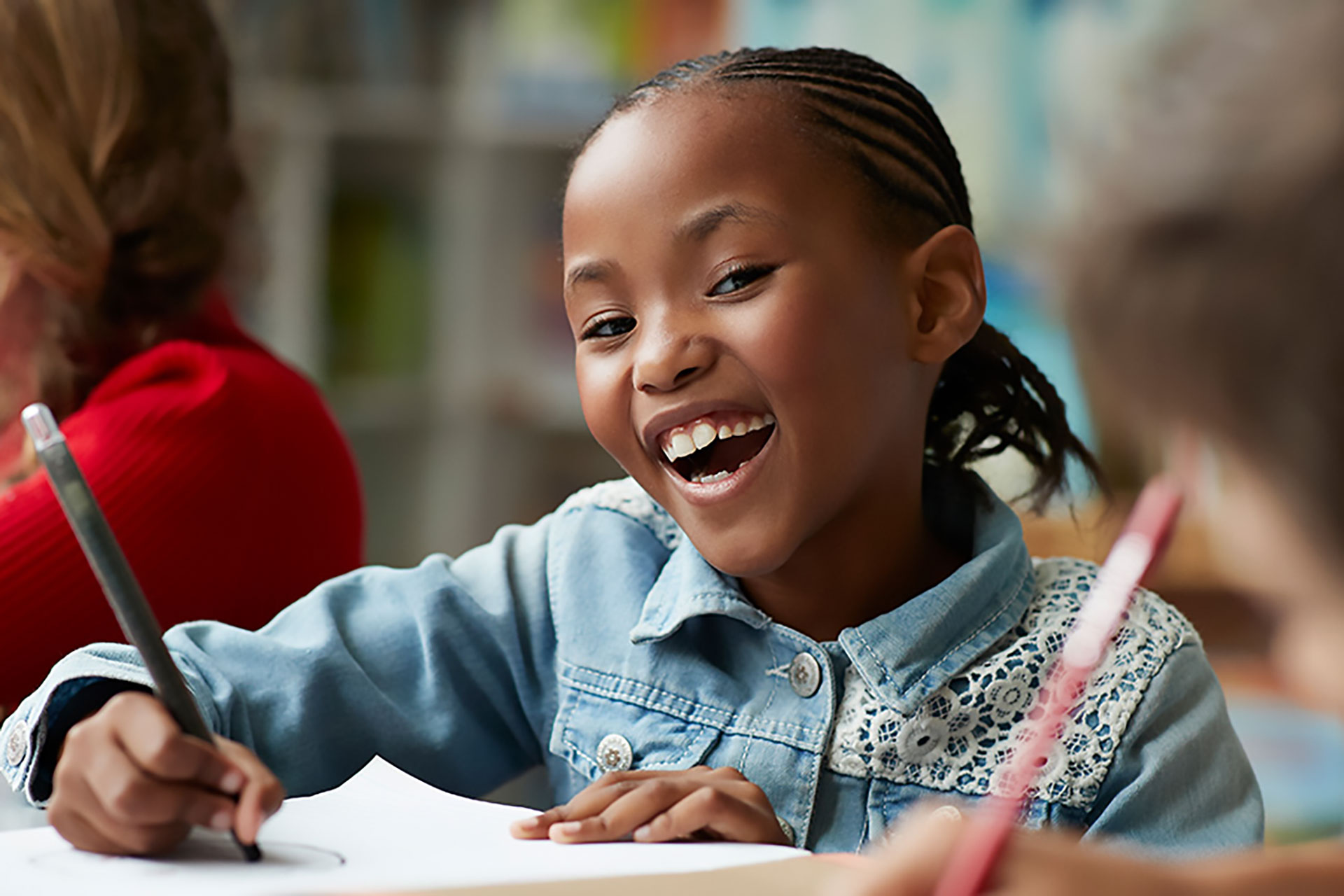 Little girl in a school setting, with a big smile on her face.