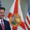 DeSantis smiles in front of flags.