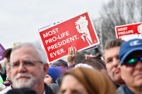 A pro-life demonstrator holds a sign with a photo of Donald Trump that reads "Most Pro-Life President Ever."