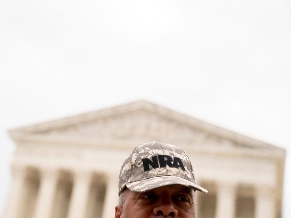 A person wears an NRA hat in front of the US Supreme Court