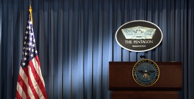 The Pentagon logo and an American flag are lit up in the briefing room of the Pentagon in Arlington, Virginia, on Jan. 3, 2002.