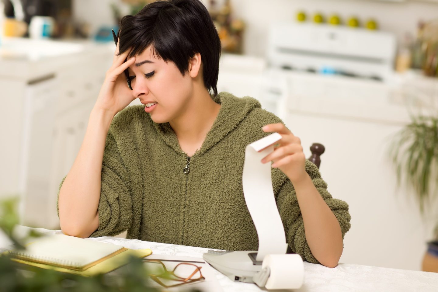 Mixed Race Young Woman Agonizing Over Financial Calculations in Kitchen