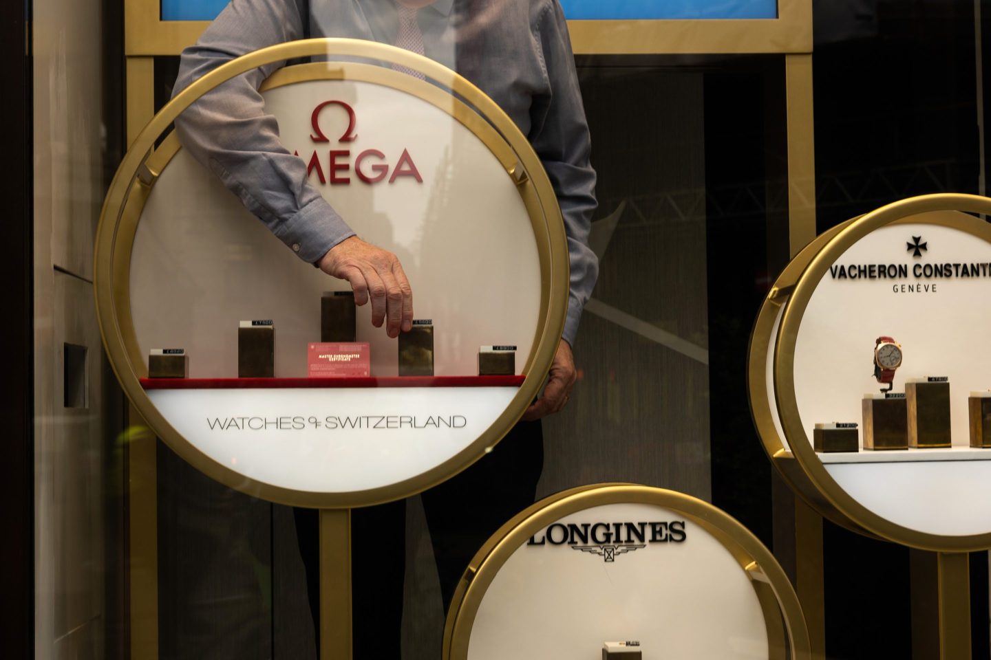 An employee arranges a display of Omega SA watches in the window of a Watches of Switzerland Group Plc store on Regent Street in London