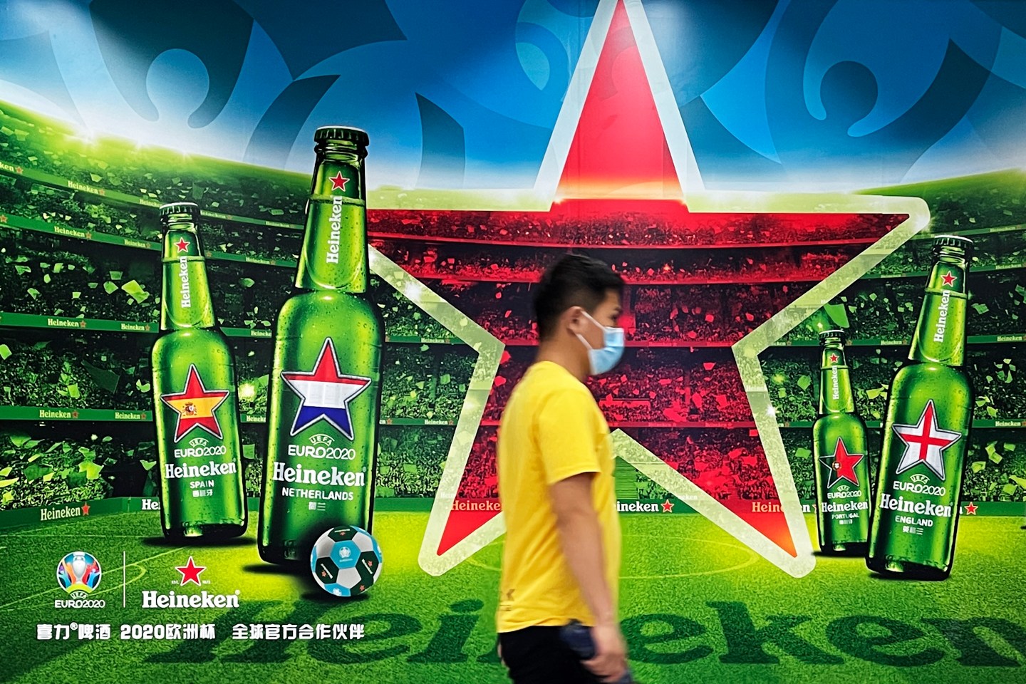 A man walks past an advertisement for Heineken beer in Beijing.