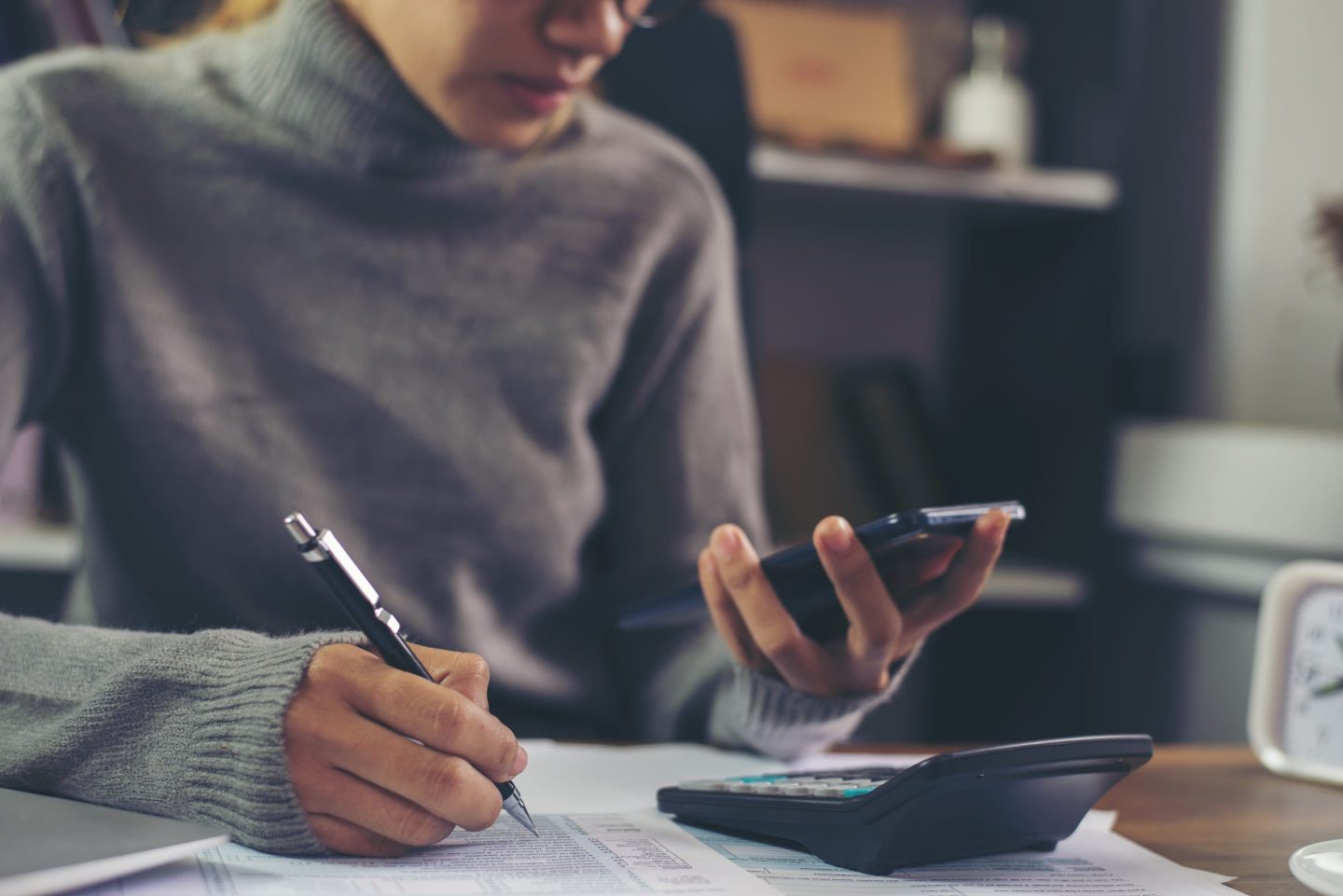 Season to pay Tax, Budget, and Tax planning concept. Business woman wear glasses calculating annual tax and using mobile phone. Calendar 2021 and personal income tax form placed on home office desk.