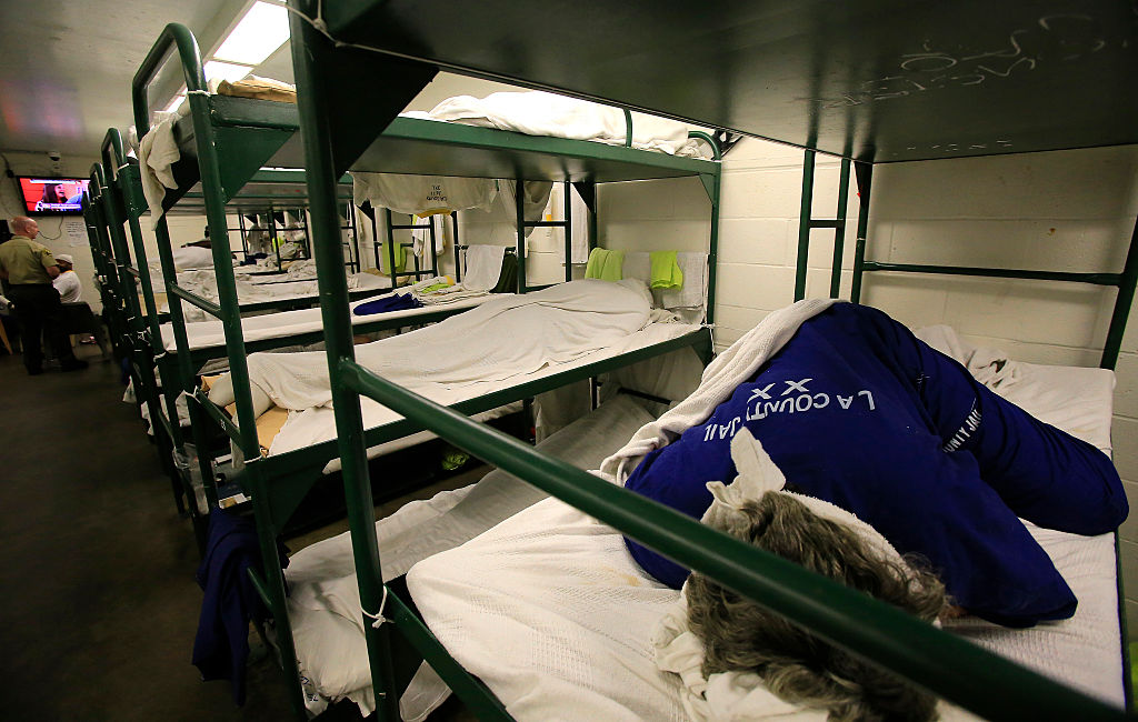 An inmate laying on a bed in a cell