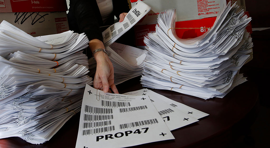 A person handling stacks of papers related to Prop. 47 in California