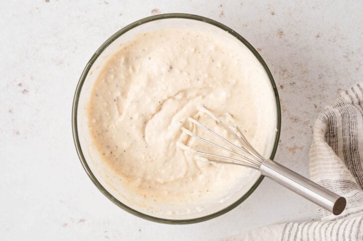 A glass bowl filled with homemade creamy Caesar dressing.