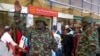 A Kenyan police officer gestures as stranded passengers wait for their delayed flights at Jomo Kenyatta International Airport after flights were grounded following workers’ protesting a planned deal between the government and a foreign investor, in Nairobi, Sept. 11, 2024.