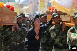 Mourners chant slogans against the Islamic State group during the funeral procession of three members of a Shi'ite group, Asa'ib Ahl al-Haq, who were killed in Tikrit, in Najaf, March 11, 2015.