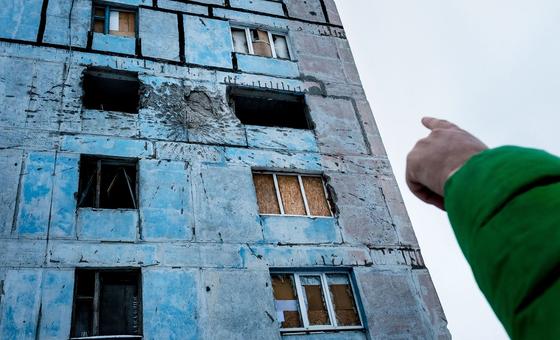 Uma criança aponta para danos em sua antiga casa em Donetsk Oblast, Ucrânia