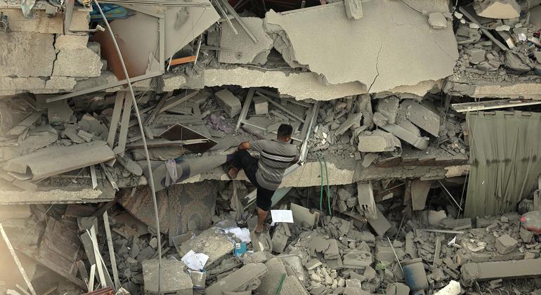 Um homem escala edifício destruído em Gaza