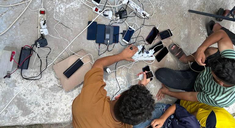 As pessoas impactadas pelo conflito em Gaza recarregam seus celulares