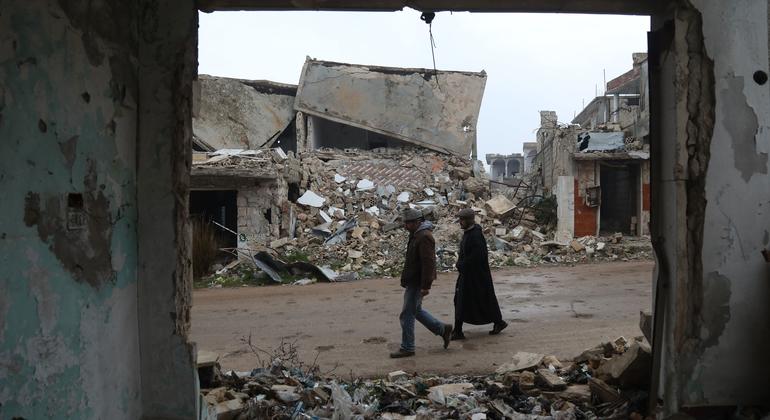 Deux personnes marchent parmi les vestiges bombardés du village de Bara, dans l'ouest de la Syrie.