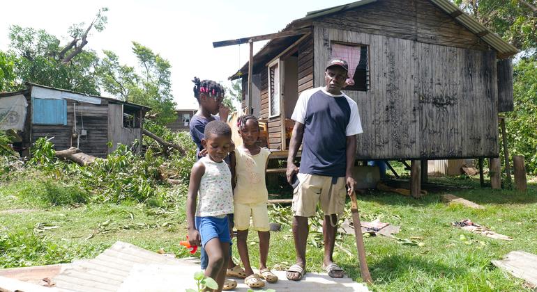 A family stands outside their home damaged by Hurricane Beryl in St. Andrews, Grenada.