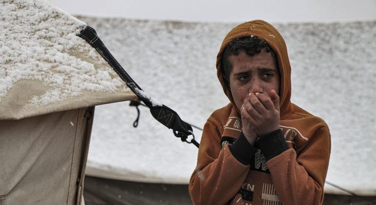 Um menino sopra em suas mãos para aquecê-los no campo de Killi em Idlib durante os rigorosos meses de inverno no noroeste da Síria.