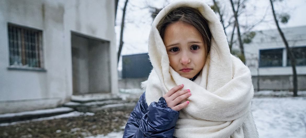 Uma menina de 8 anos posa em frente a um prédio em Irpin, na Ucrânia, onde sua mãe e sua irmã dividem um pequeno quarto.