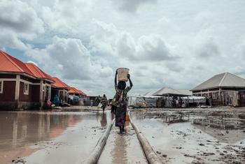 Millions remain displaced across Nigeria due to conflict, climate change impacts and natural disasters. In this file photo, a girl carries water to her shelter at an IDP camp in the country's northeast.