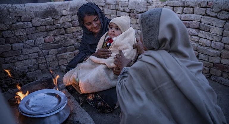 Nadiya mantém seu filho de 8 meses, Ataullah, aquecido em frente ao fogão no Paquistão.
