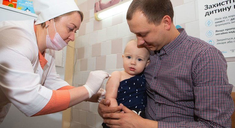 A baby is held by his father as a nurse administers his first dose of MMR vaccine from measles, mumps and rubella.