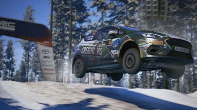 EA Sports WRC — снимок экрана, на котором M-Sport Poland Fiesta Rally3 Уильяма Крейтона летит в воздухе посреди заснеженного леса